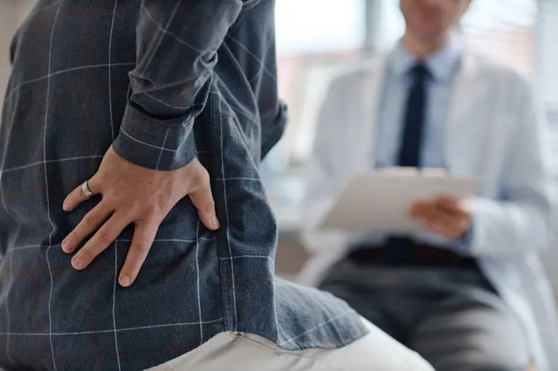 When should patients see a rheumatologist for chronic back pain?