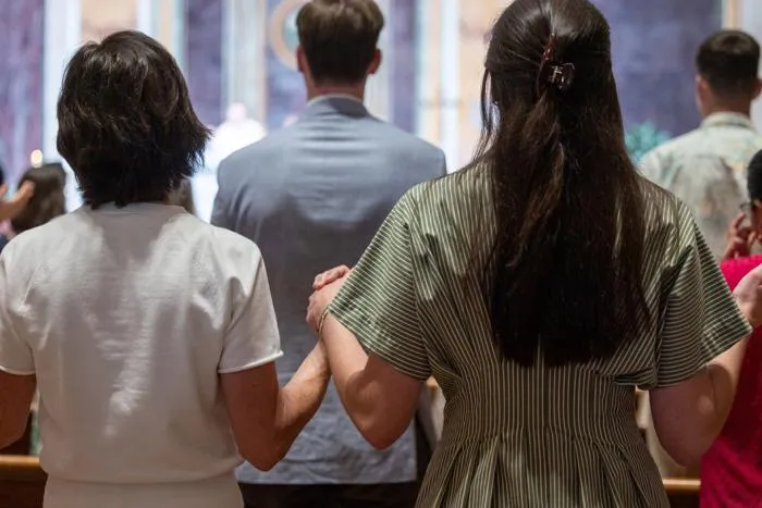 Is it appropriate to hold hands or lift your hands up during the Our Father at Mass?