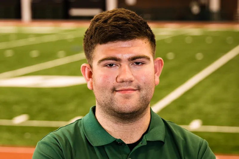 Sports media student gaining experience behind the plate, microphone