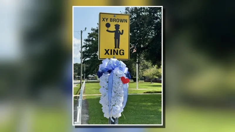 Wreath placed at Northwoods Elementary beneath "XY Brown Xing" sign after his death
