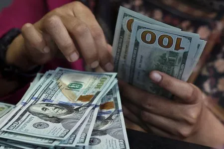 Dollar holds losses as markets await Fed minutes, speakers